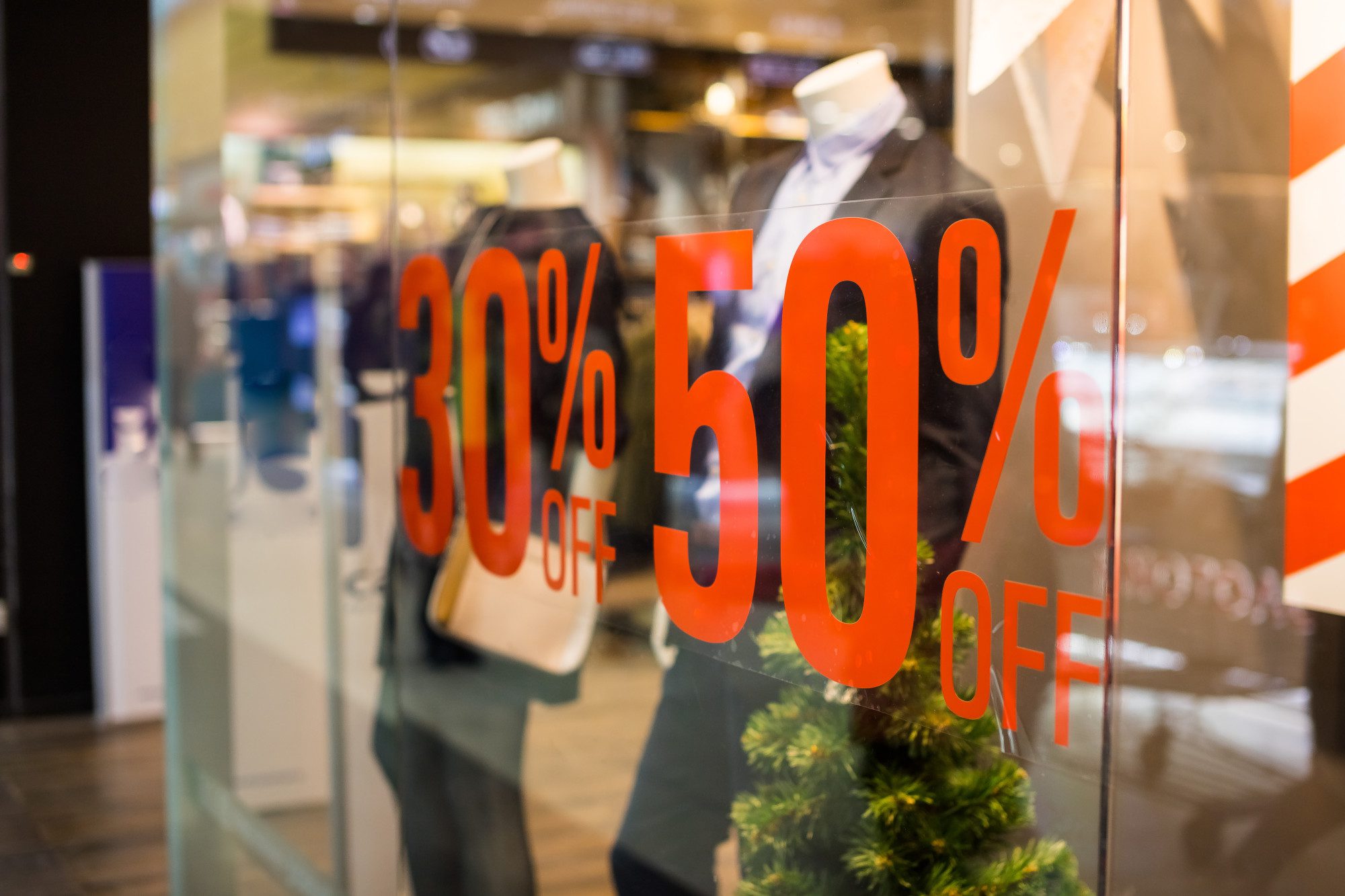 Shopping sale sign Sign of sale shoppingdiscount sign on show window Sale sign symbol in clothes shopThe red announcement of a fifty percentage discount on a glass show window Copy space